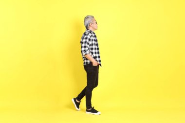 The 40s adult Asian man with casual dressed standing on the yellow background.