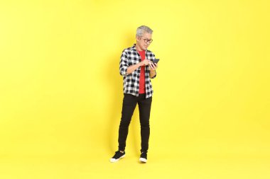 The 40s adult Asian man with casual dressed standing on the yellow background.