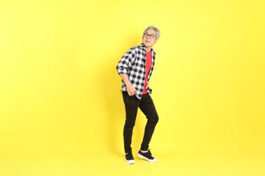 The 40s adult Asian man with casual dressed standing on the yellow background.