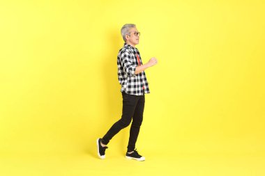 The 40s adult Asian man with casual dressed standing on the yellow background.