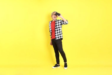 The 40s adult Asian man with casual dressed standing on the yellow background.