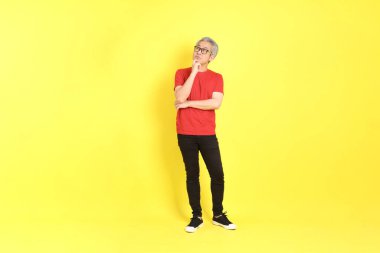 The 40s adult Asian man with casual dressed standing on the yellow background.