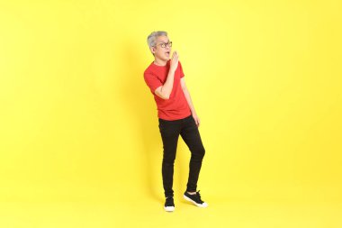 The 40s adult Asian man with casual dressed standing on the yellow background.