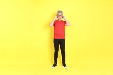 The 40s adult Asian man with casual dressed standing on the yellow background.