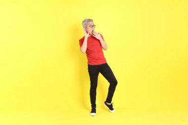The 40s adult Asian man with casual dressed standing on the yellow background.