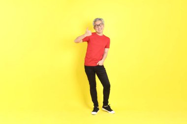 The 40s adult Asian man with casual dressed standing on the yellow background.