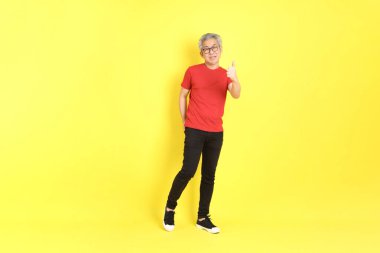 The 40s adult Asian man with casual dressed standing on the yellow background.