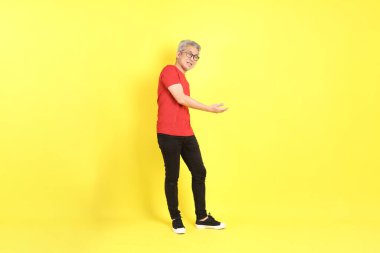 The 40s adult Asian man with casual dressed standing on the yellow background.