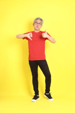The 40s adult Asian man with casual dressed standing on the yellow background.