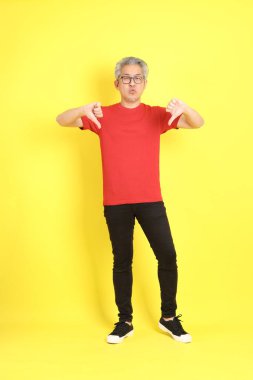 The 40s adult Asian man with casual dressed standing on the yellow background.