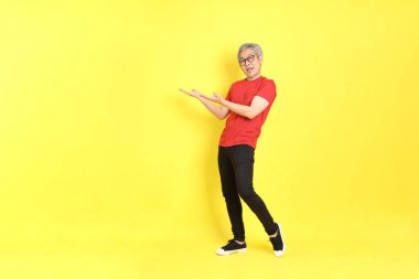 The 40s adult Asian man with casual dressed standing on the yellow background.