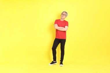The 40s adult Asian man with casual dressed standing on the yellow background.