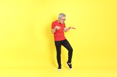 The 40s adult Asian man with casual dressed standing on the yellow background.
