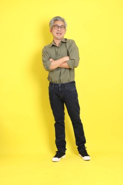The 40s adult Asian man with casual dressed standing on the yellow background.