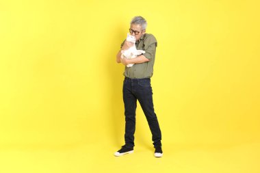 The 40s adult Asian man with casual dressed standing on the yellow background.