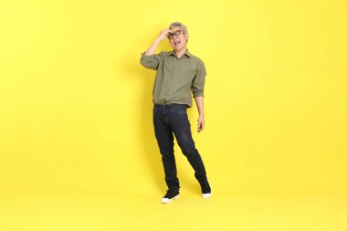 The 40s adult Asian man with casual dressed standing on the yellow background.
