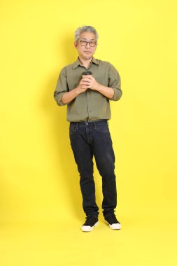The 40s adult Asian man with casual dressed standing on the yellow background.