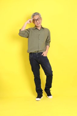The 40s adult Asian man with casual dressed standing on the yellow background.
