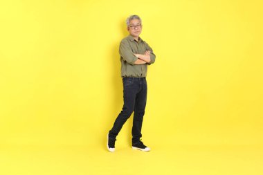 The 40s adult Asian man with casual dressed standing on the yellow background.