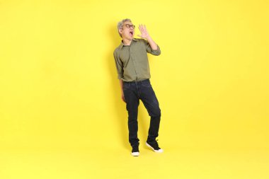 The 40s adult Asian man with casual dressed standing on the yellow background.