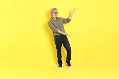 The 40s adult Asian man with casual dressed standing on the yellow background.