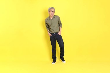 The 40s adult Asian man with casual dressed standing on the yellow background.