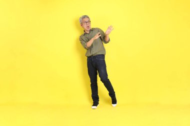 The 40s adult Asian man with casual dressed standing on the yellow background.