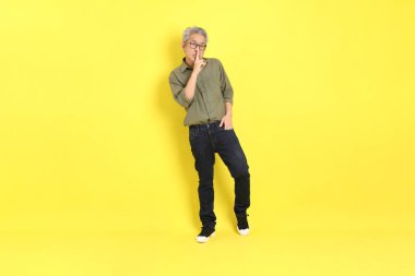 The 40s adult Asian man with casual dressed standing on the yellow background.