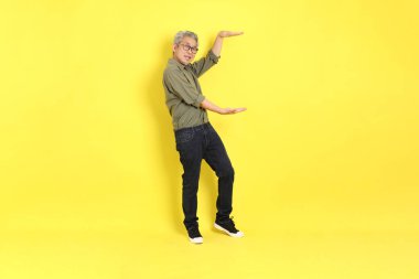The 40s adult Asian man with casual dressed standing on the yellow background.