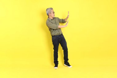 The 40s adult Asian man with casual dressed standing on the yellow background.