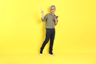 The 40s adult Asian man with casual dressed standing on the yellow background.