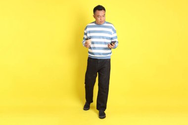 The 40s adult Asian man with standing on the yellow background.