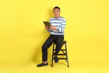 The 40s adult Asian man with sitting on the yellow background.
