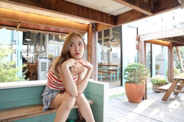 Yakışıklı Asyalı kadın halk parkında poz verirken rahatlıyor..