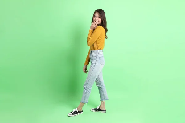 Yeşil Arka Planda Duran Sıradan Giyinmiş Kot Pantolonlu Genç Asyalı — Stok fotoğraf
