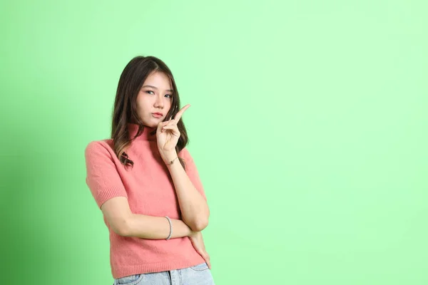 stock image The young adult Asian woman with casual clothes with jeans standing on the green background.