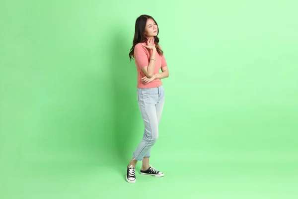 stock image The young adult Asian woman with casual clothes with jeans standing on the green background.