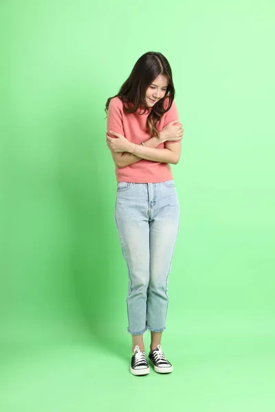 Yeşil Arka Planda Duran Sıradan Giyinmiş Kot Pantolonlu Genç Asyalı — Stok fotoğraf