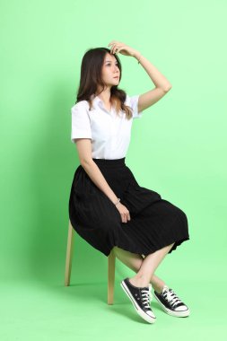 Yeşil arka planda duran üniformalı genç kız..