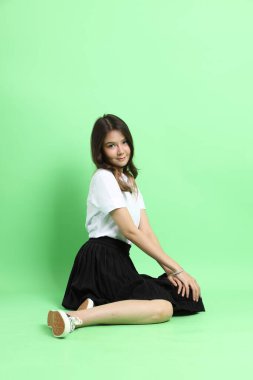 Yeşil arka planda duran üniformalı genç kız..