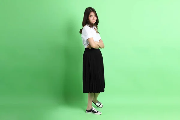 Fiatal Iskolás Lány Egyenruhában Áll Zöld Háttéren — Stock Fotó