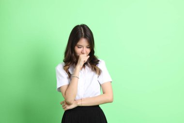 Yeşil arka planda duran üniformalı genç kız..