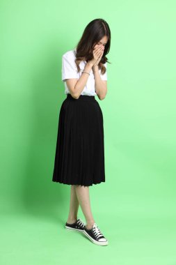 Yeşil arka planda duran üniformalı genç kız..