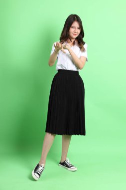 Yeşil arka planda duran üniformalı genç kız..