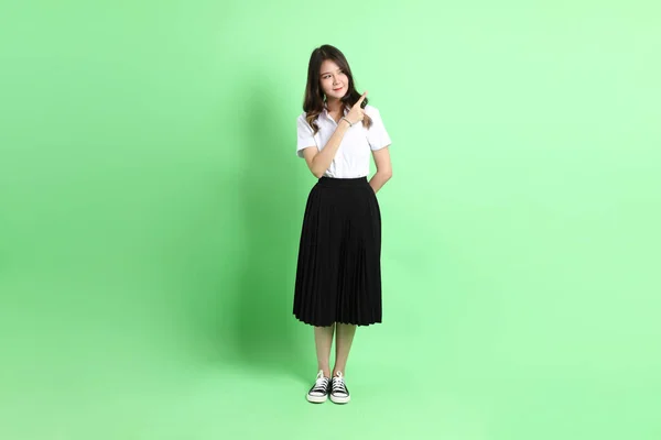 Fiatal Iskolás Lány Egyenruhában Áll Zöld Háttéren — Stock Fotó