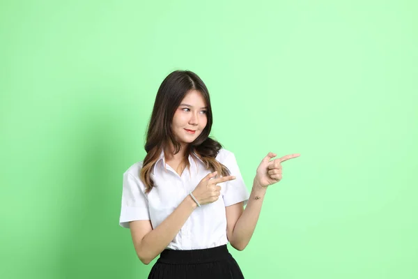 Stock image The young school girl with uniform standing on the green background.