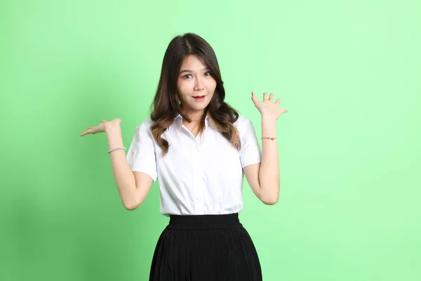 stock image The young school girl with uniform standing on the green background.