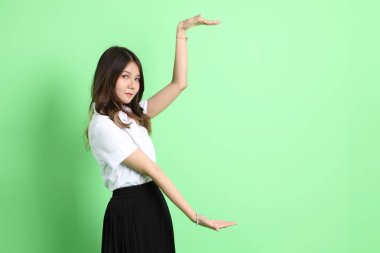 Yeşil arka planda duran üniformalı genç kız..