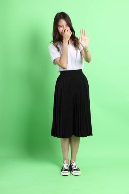 Yeşil arka planda duran üniformalı genç kız..