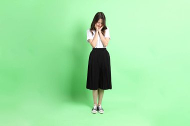 Yeşil arka planda duran üniformalı genç kız..